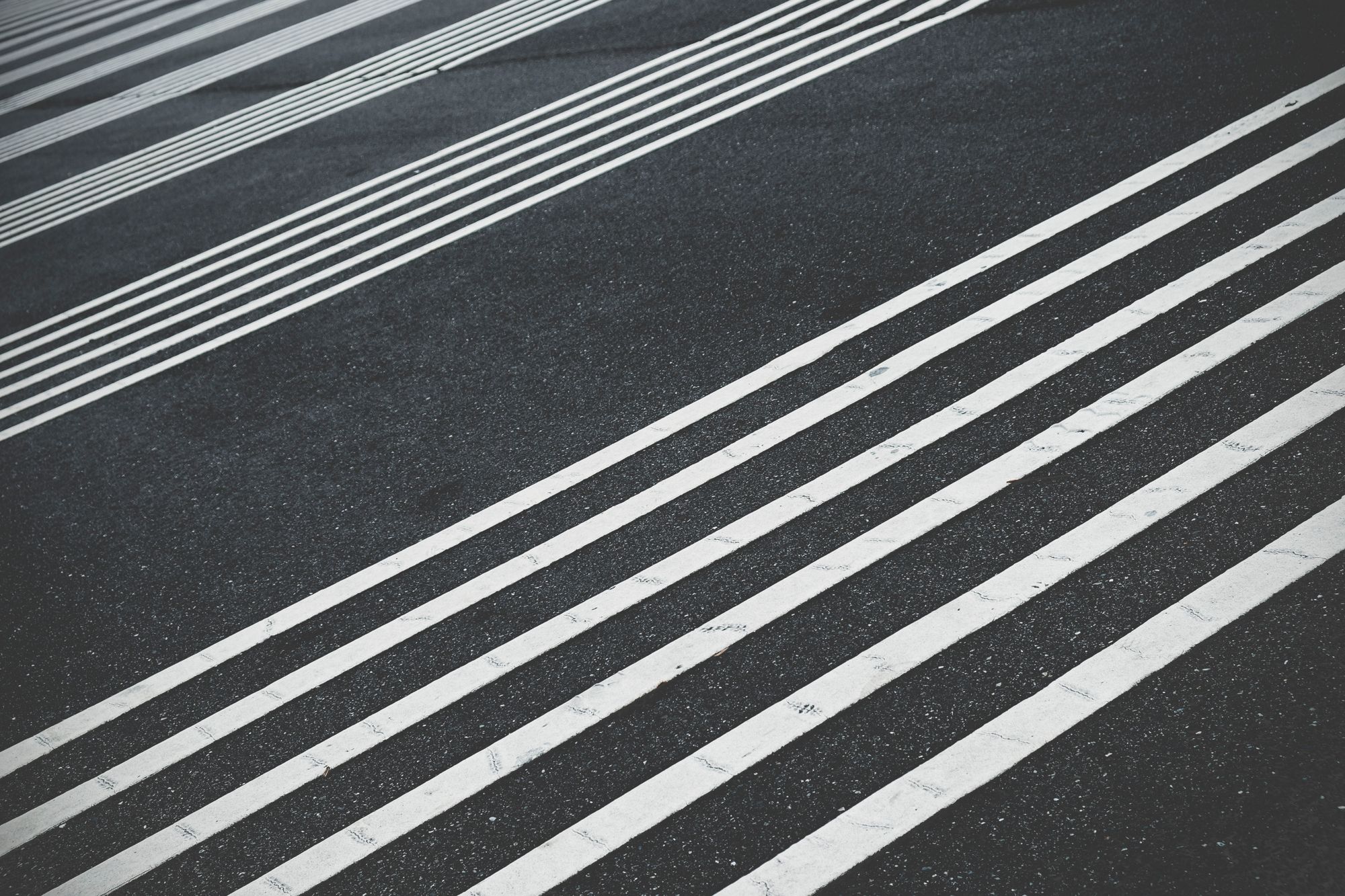 Parallel straight white lines ruled across grainy dark asphalt, evoking a linear regression fit