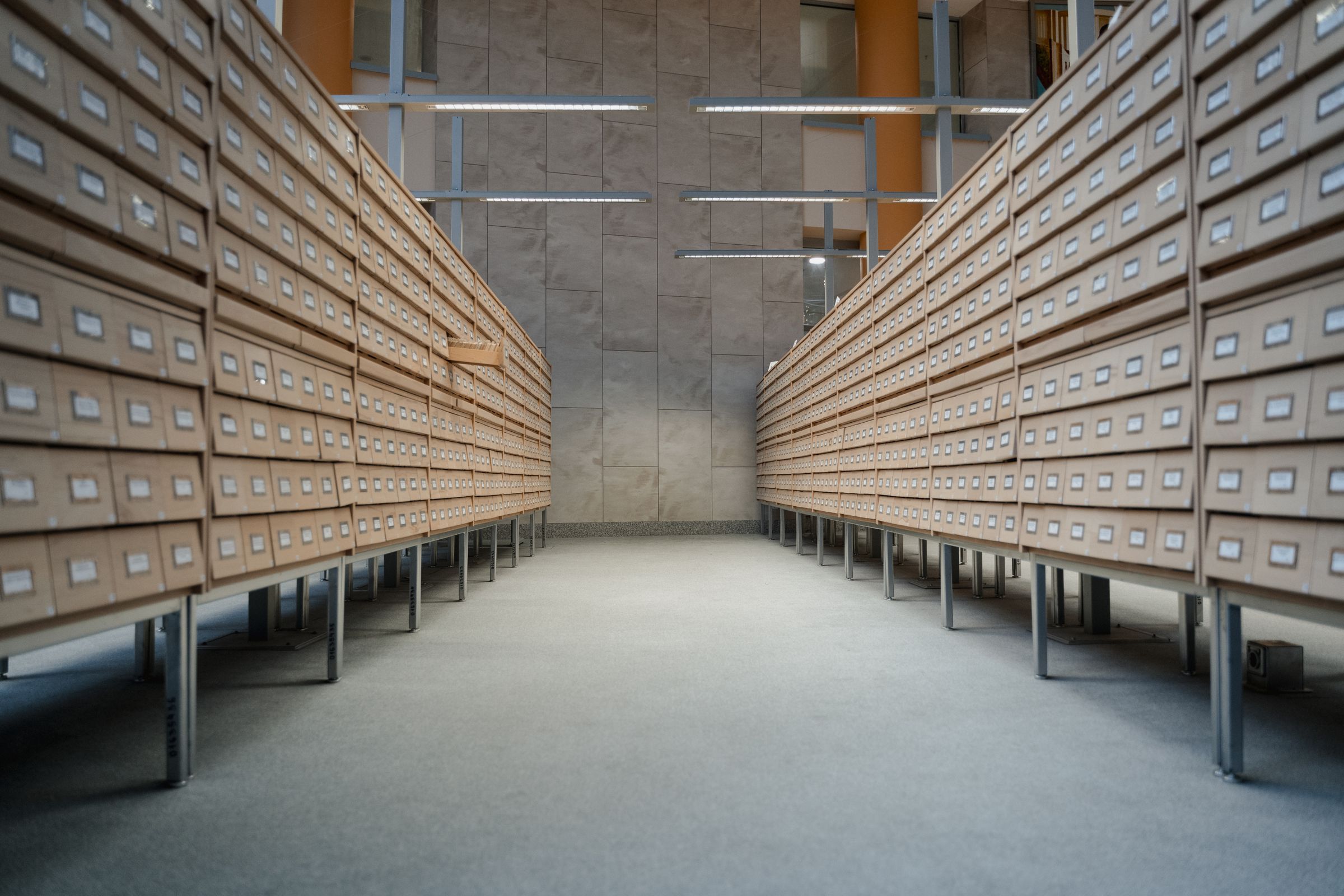 Long corridor of wooden card catalog drawers forming a file-based AI agent memory archive